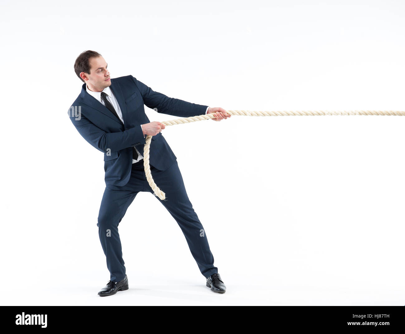 Strong and confident business leader. Side view of businessman in suit pulling a rope while standing against white background Stock Photo