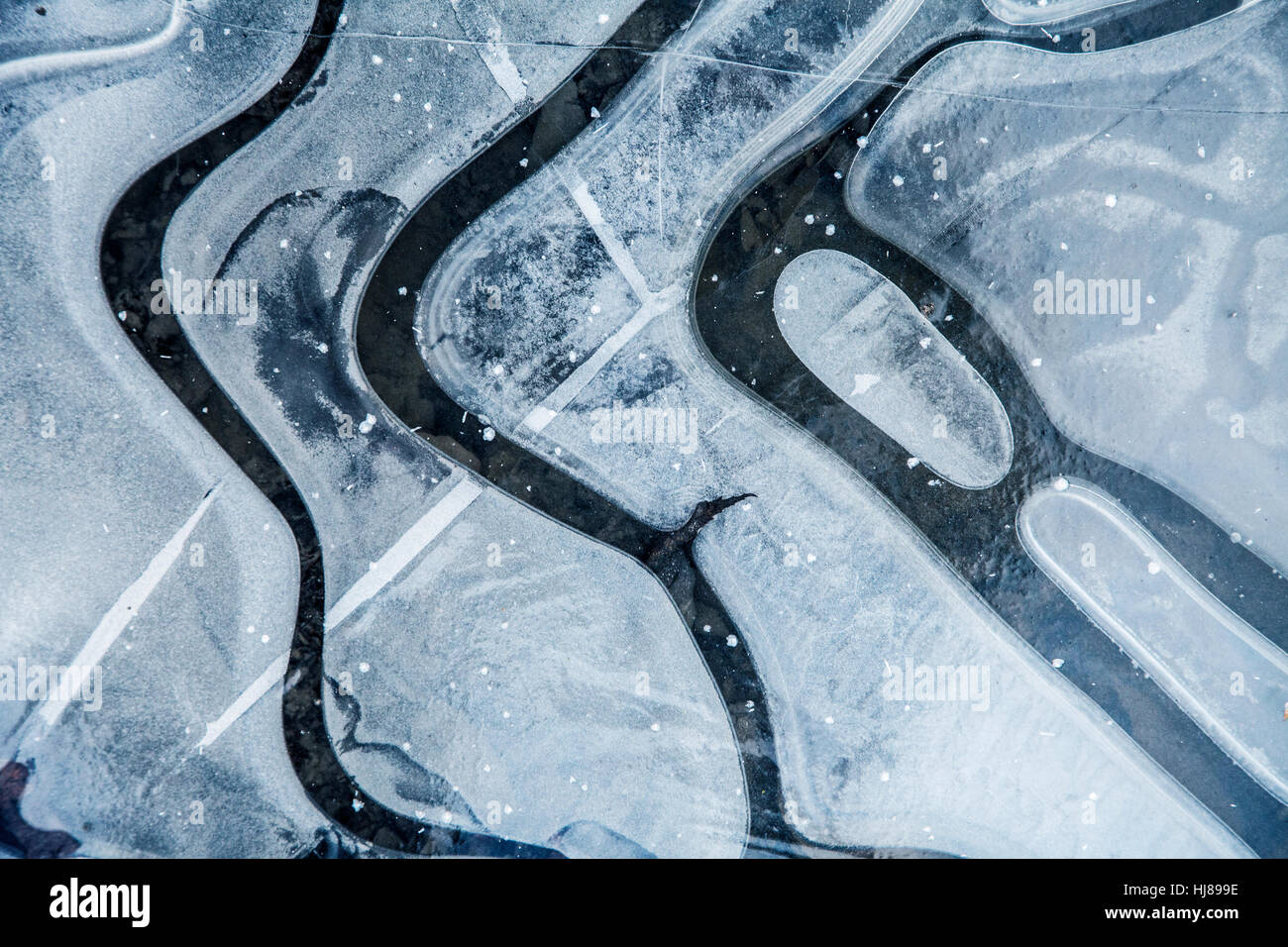 Frozen water puddle in winter blue color with lines and curves black and white abstract nature painting Stock Photo