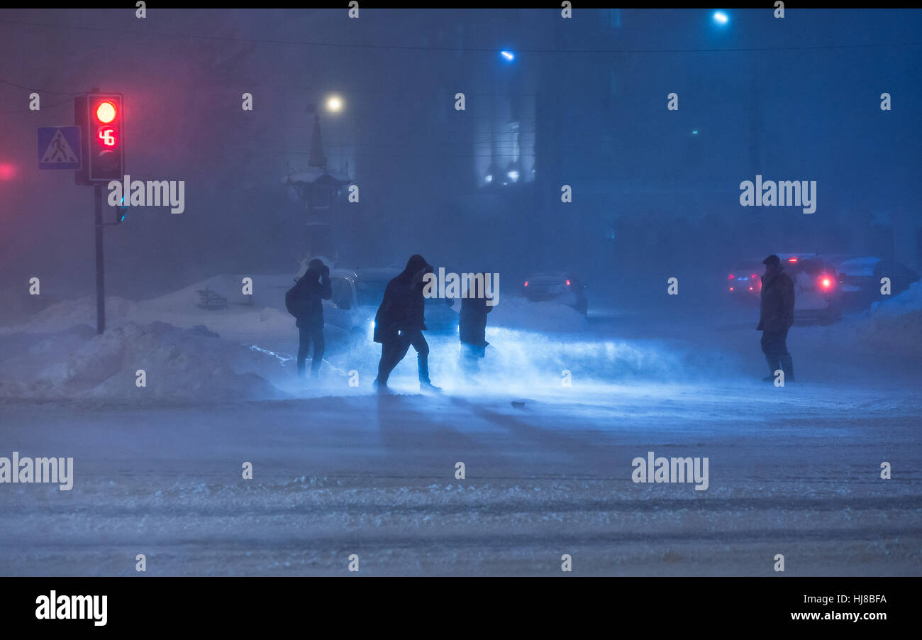 People cross road at heavy night winter snowstorm. Low visibility