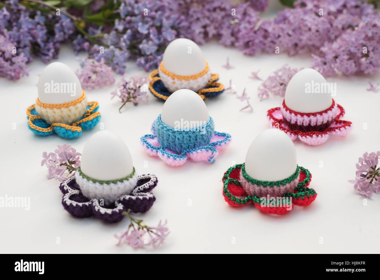 boiled eggs in crocheted egg cups with lilac flowers Stock Photo