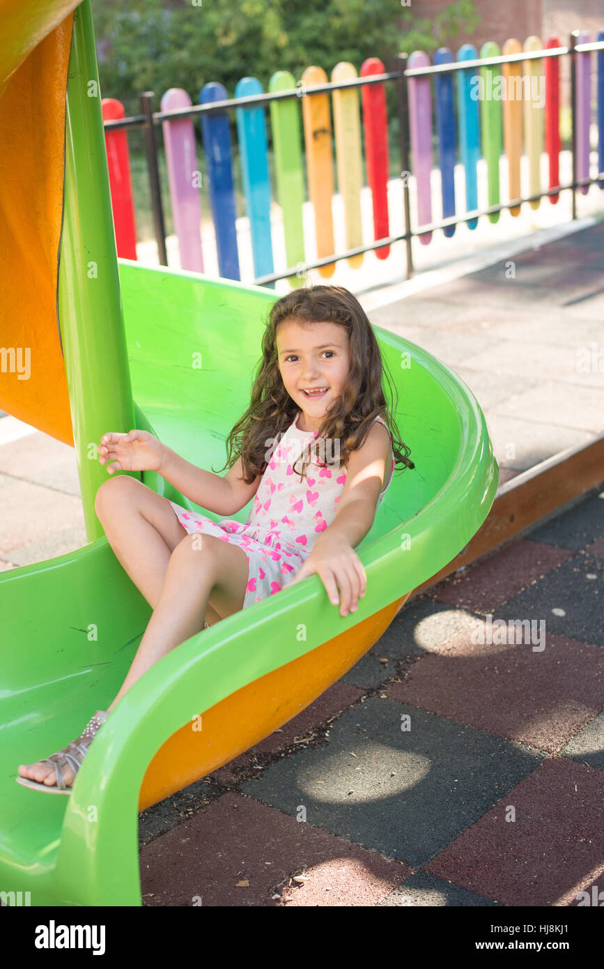 Happy girl on a slide in the playground Stock Photo