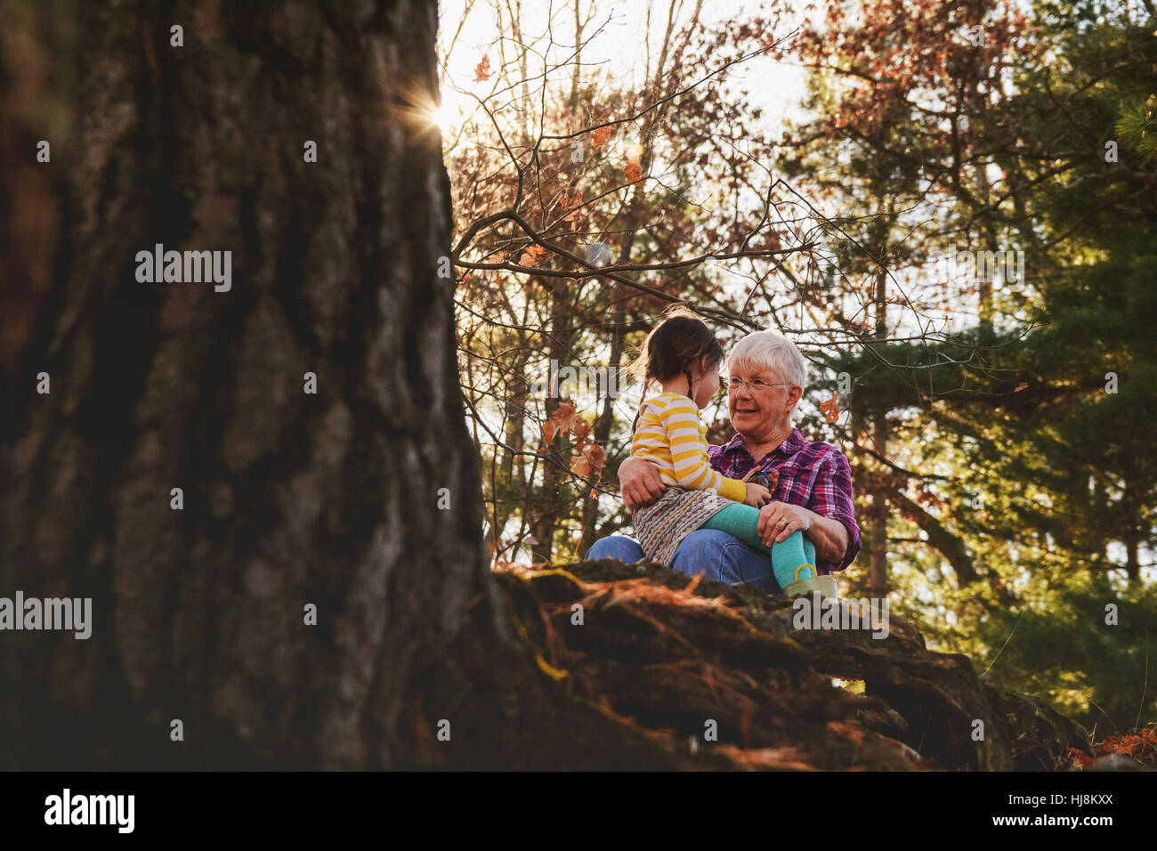 Grandmother and granddaughter sitting in forest talking Stock Photo