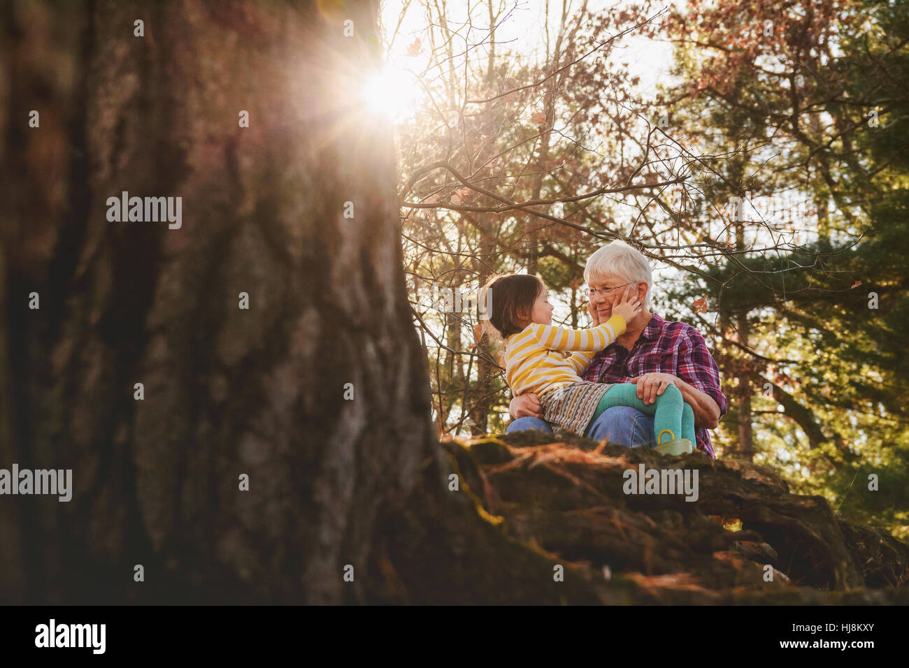 Grandmother and granddaughter sitting in forest talking Stock Photo