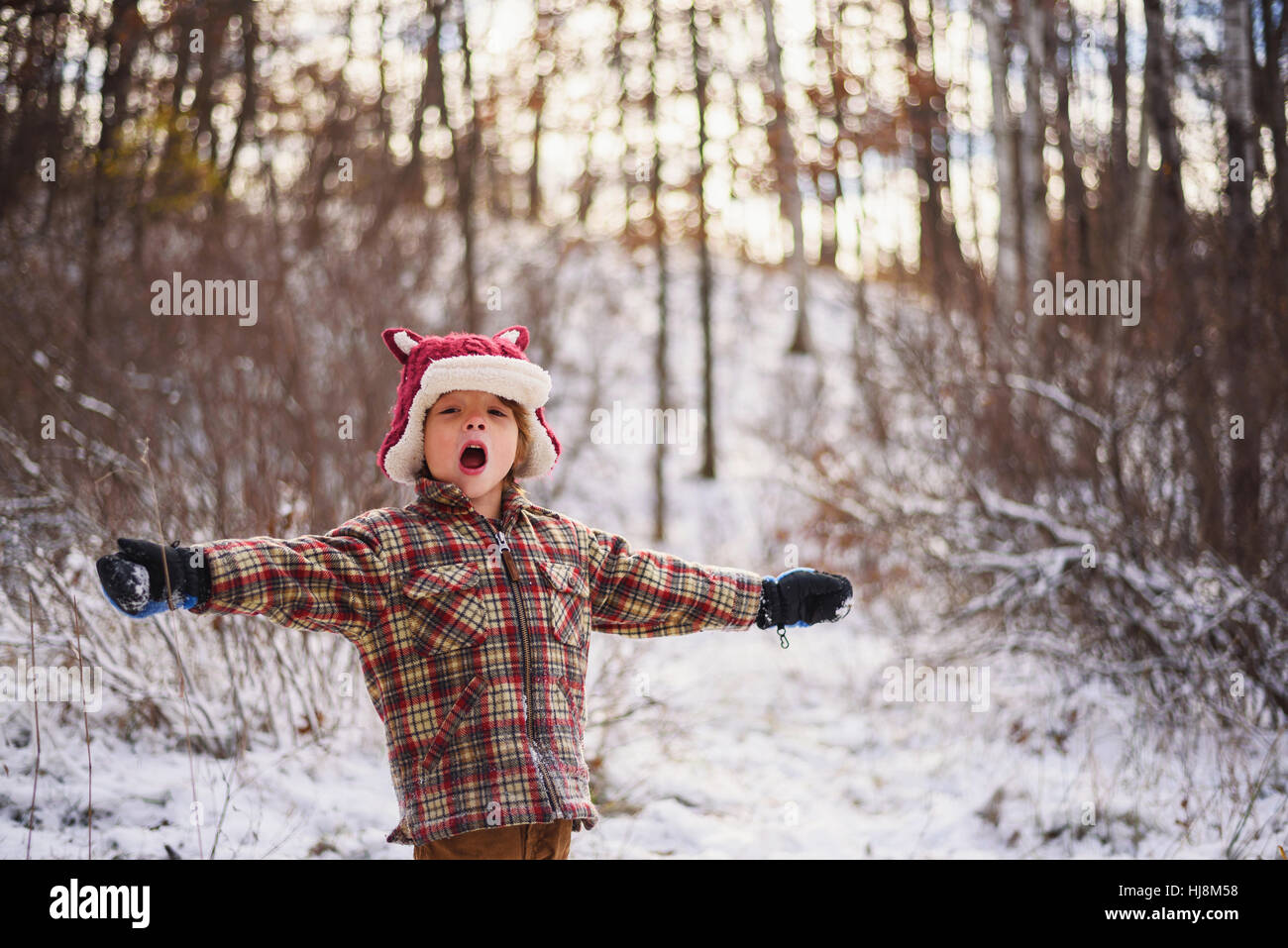 Portrait of a boy standing in snow with outstretched arms Stock Photo