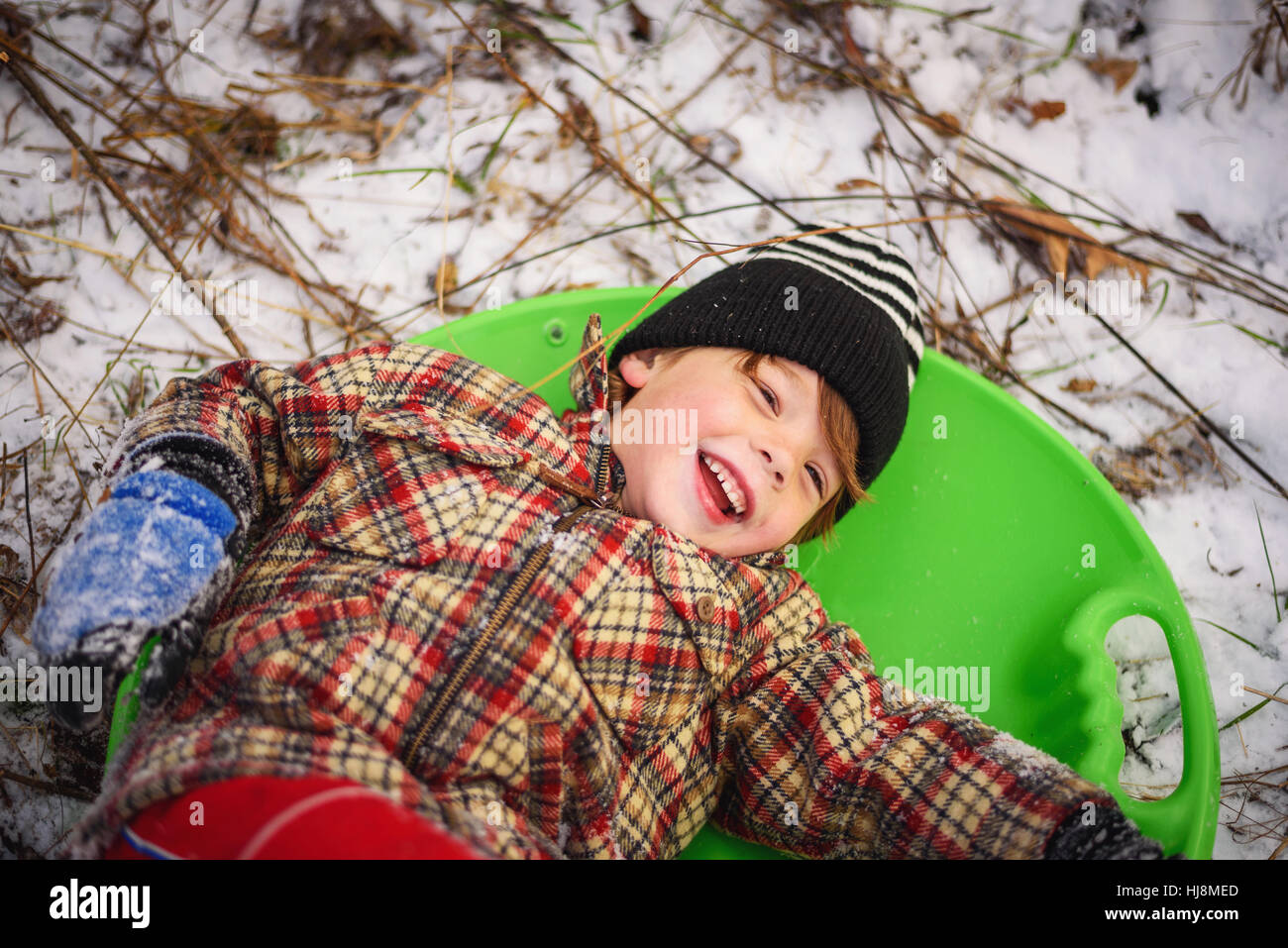 Boy lying in a sledge laughing Stock Photo