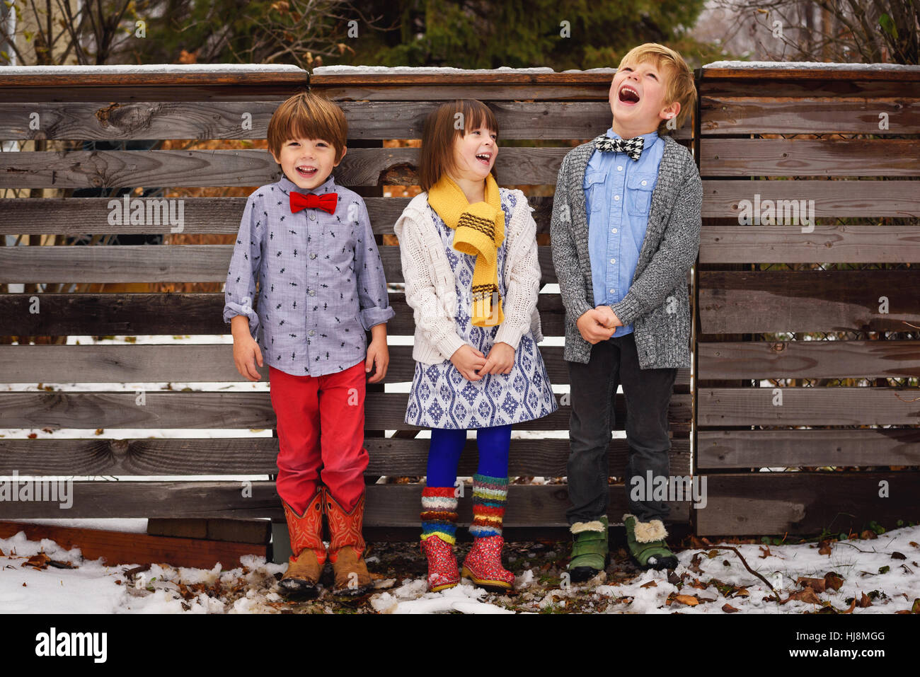Three happy children standing by a fence in the garden Stock Photo