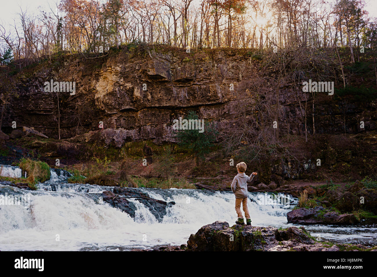 Young boy throwing rocks into a waterfall Stock Photo