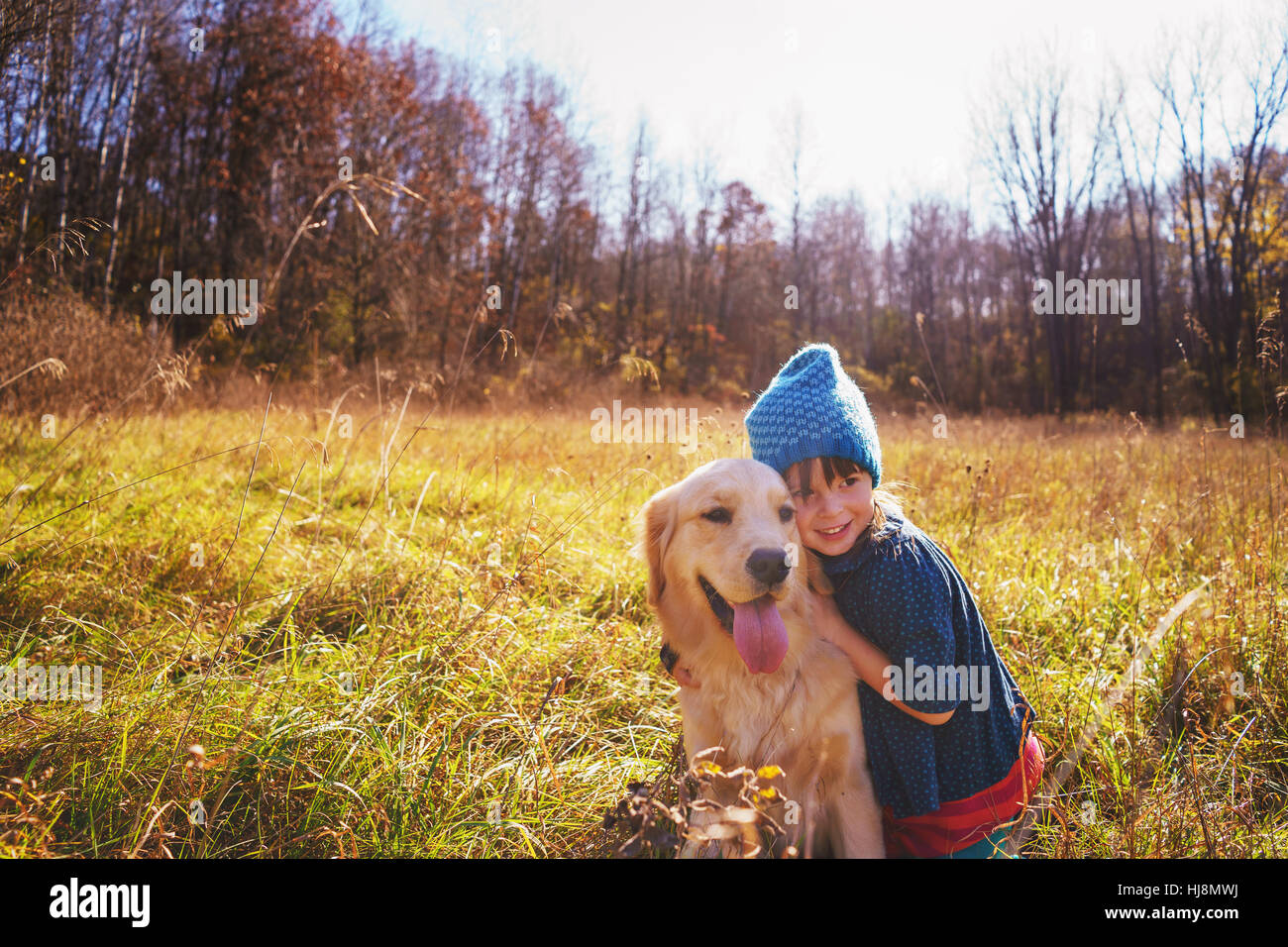 Girl with her golden retriever puppy dog Stock Photo