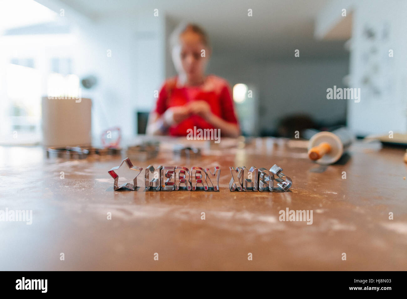 Girl baking with Merry Christmas cookie cutters on table Stock Photo