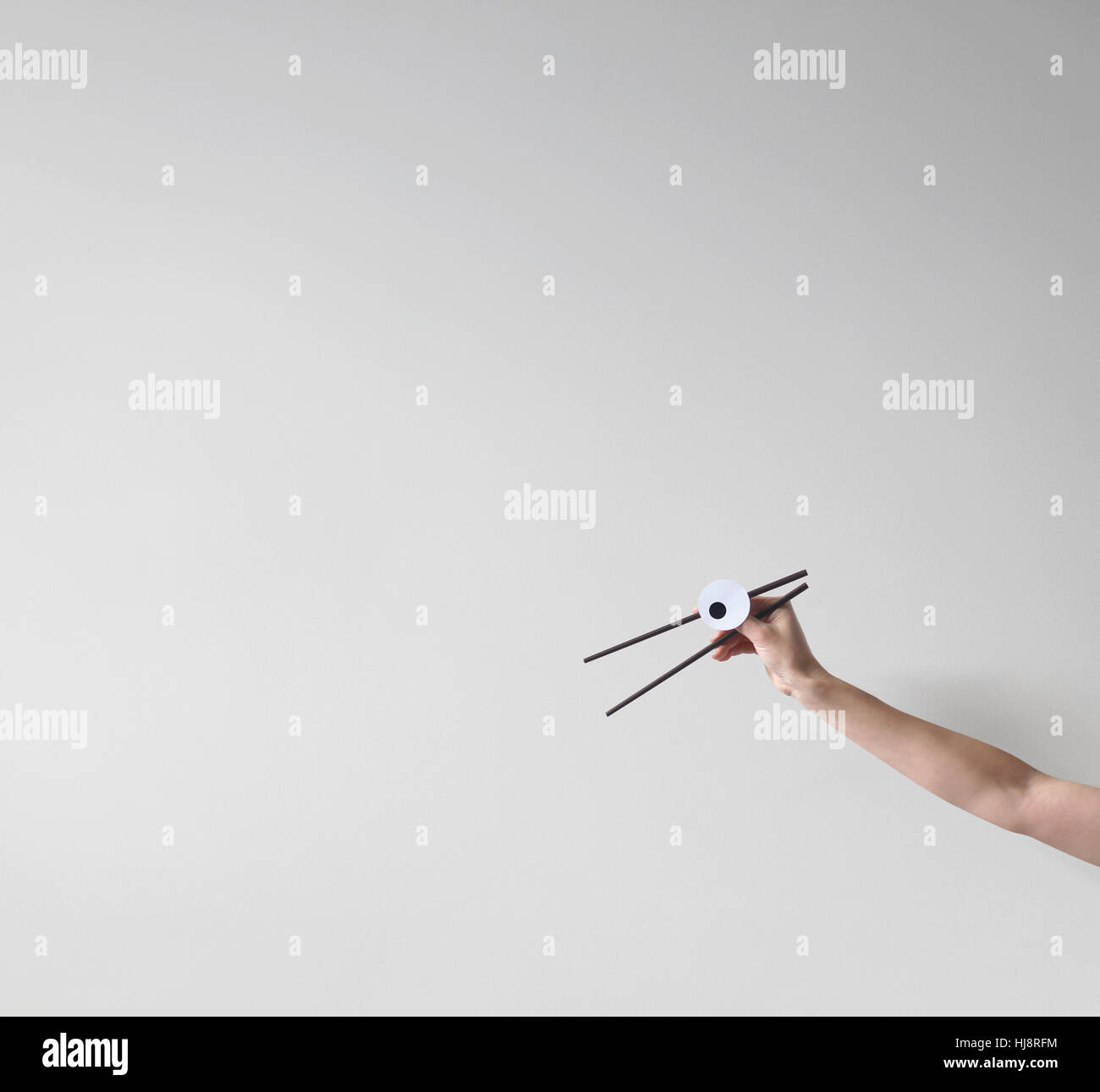 Woman's Hand holding chopsticks with googly eyes Stock Photo