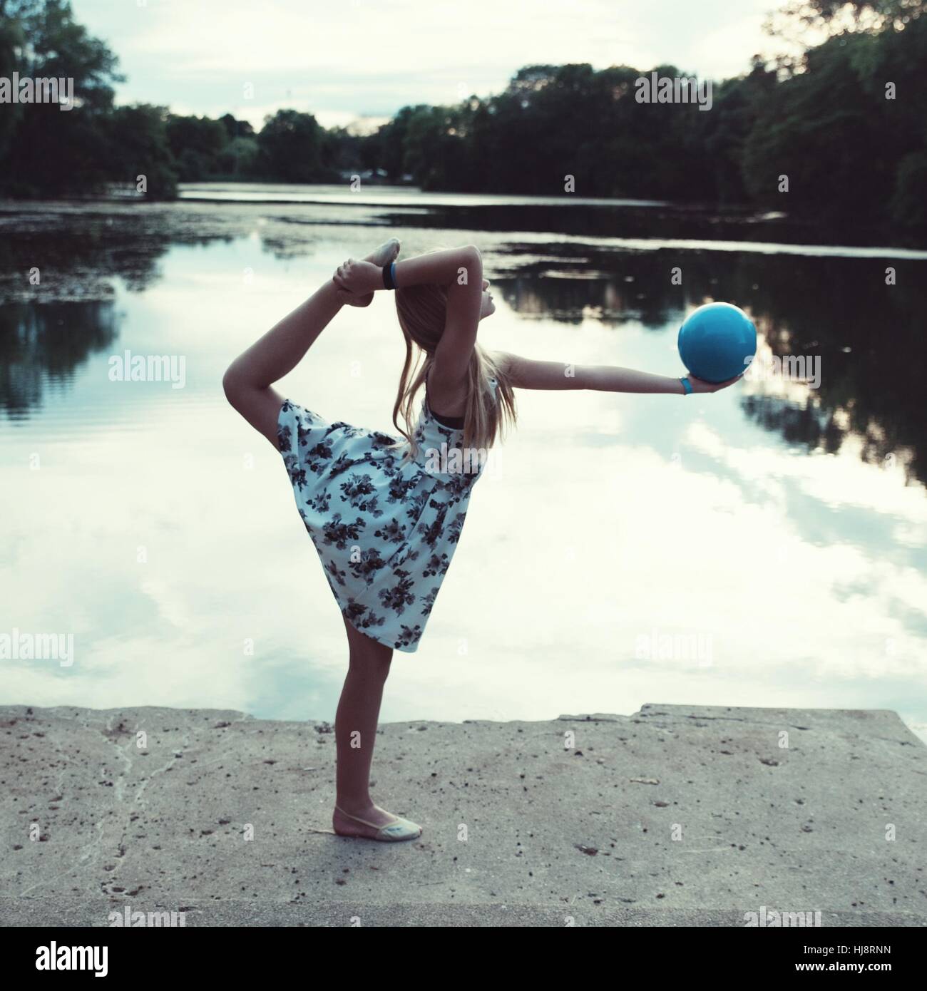 girl holding a ball standing on one leg in ring pose Stock Photo