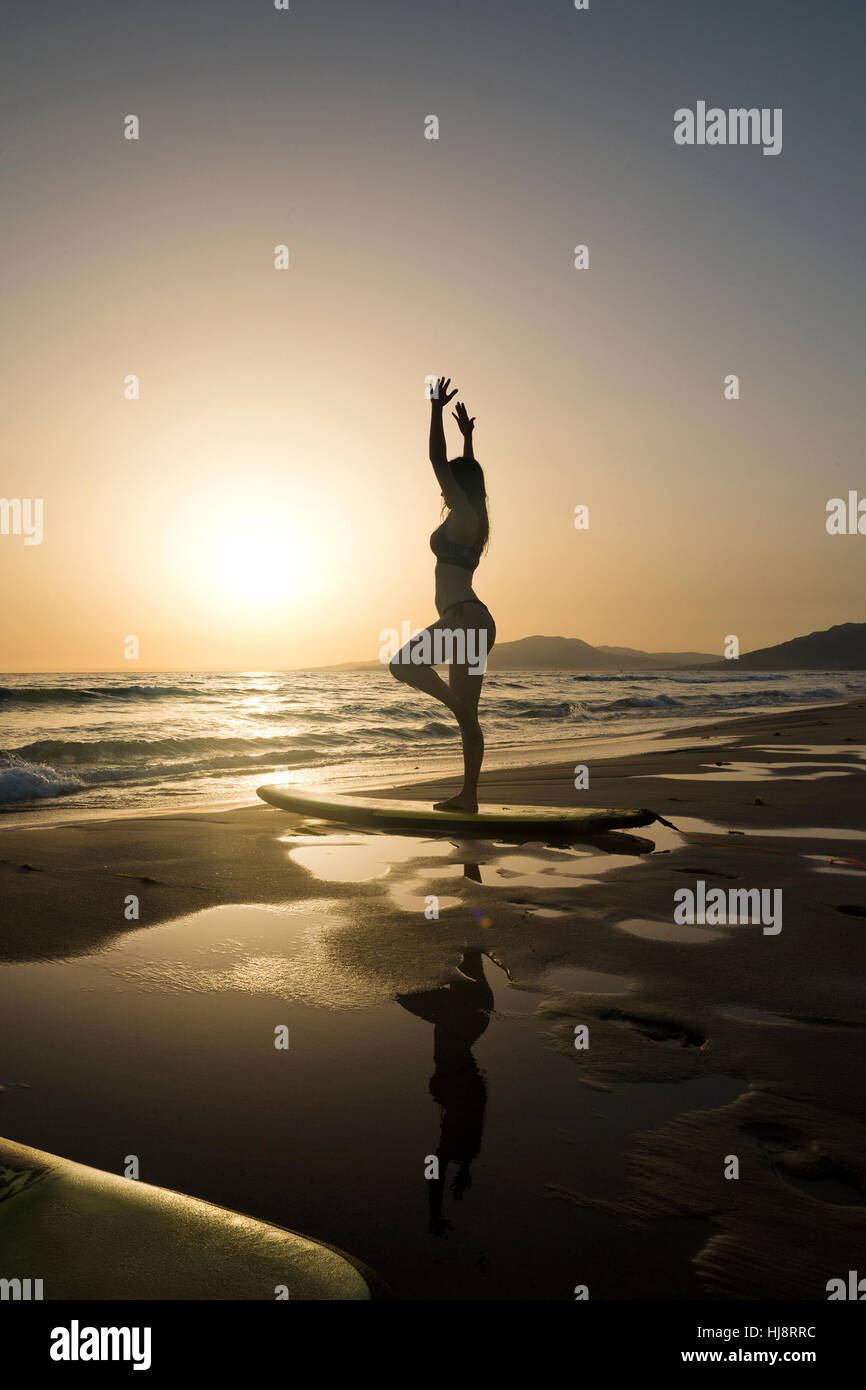 Silhouette of a woman doing yoga on a surfboard, Los Lances beach, Tarifa, Cadiz, Andalucia, Spain Stock Photo