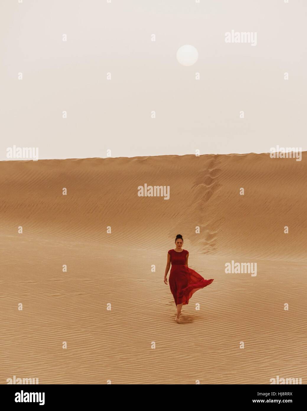 Women in red dress walking in the sand hi-res stock photography and ...