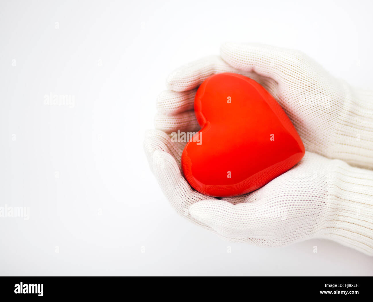 Little red heart in white warm wool gloves over white background Stock Photo