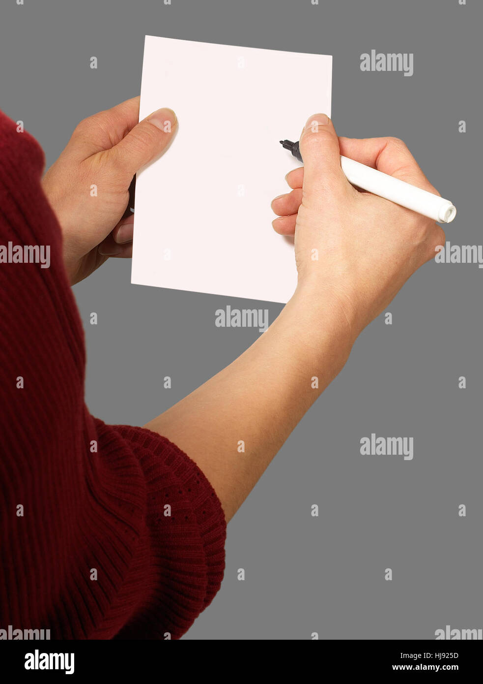 detail of a woman holding paper chit and pen in grey back Stock Photo