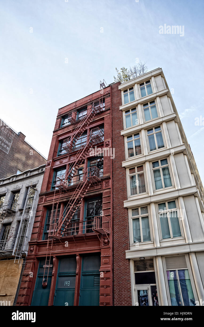 New York City, Manhattan, Soho, Houston Street.  Looking Up at Two buildings - Old Cast Iron Red One, and Beige New One. Stock Photo
