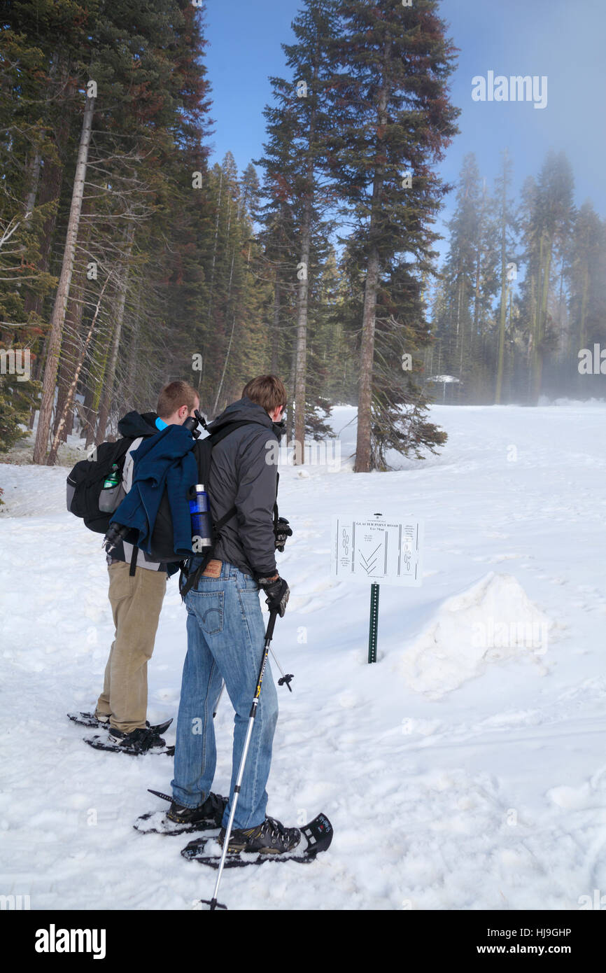 Men snowshoeing by Badger Pass at Yosemite National Park read sign about Glacier Point Road Stock Photo