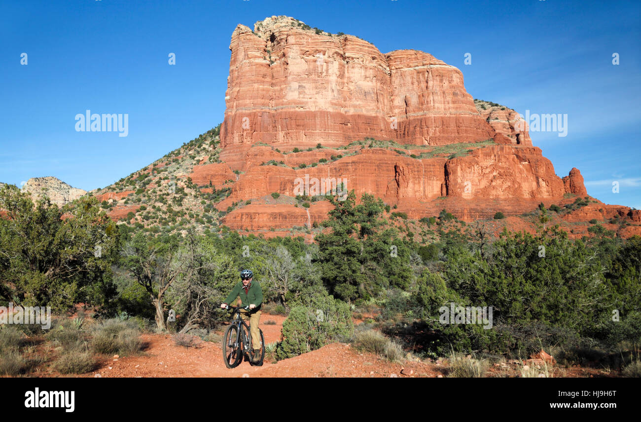 Bicyclist in front of the Courthouse Butte pedals toward the Bell Rock Pathway in the Village of Oak Creek by Sedona Stock Photo