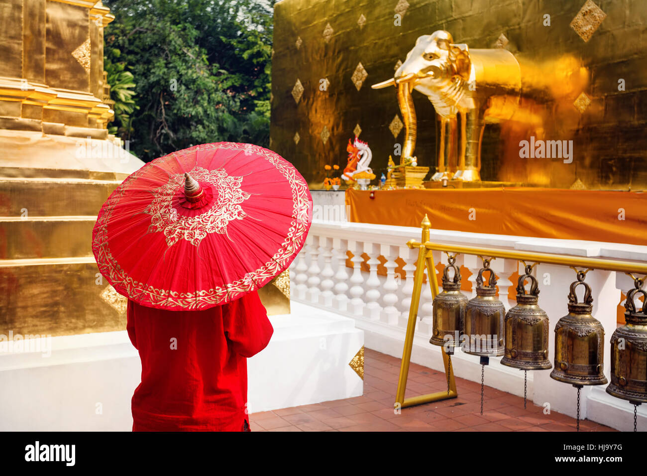 Woman tourist with red traditional Thai umbrella in Golden temple Wat Phra Singh in Chiang Mai, Thailand Stock Photo