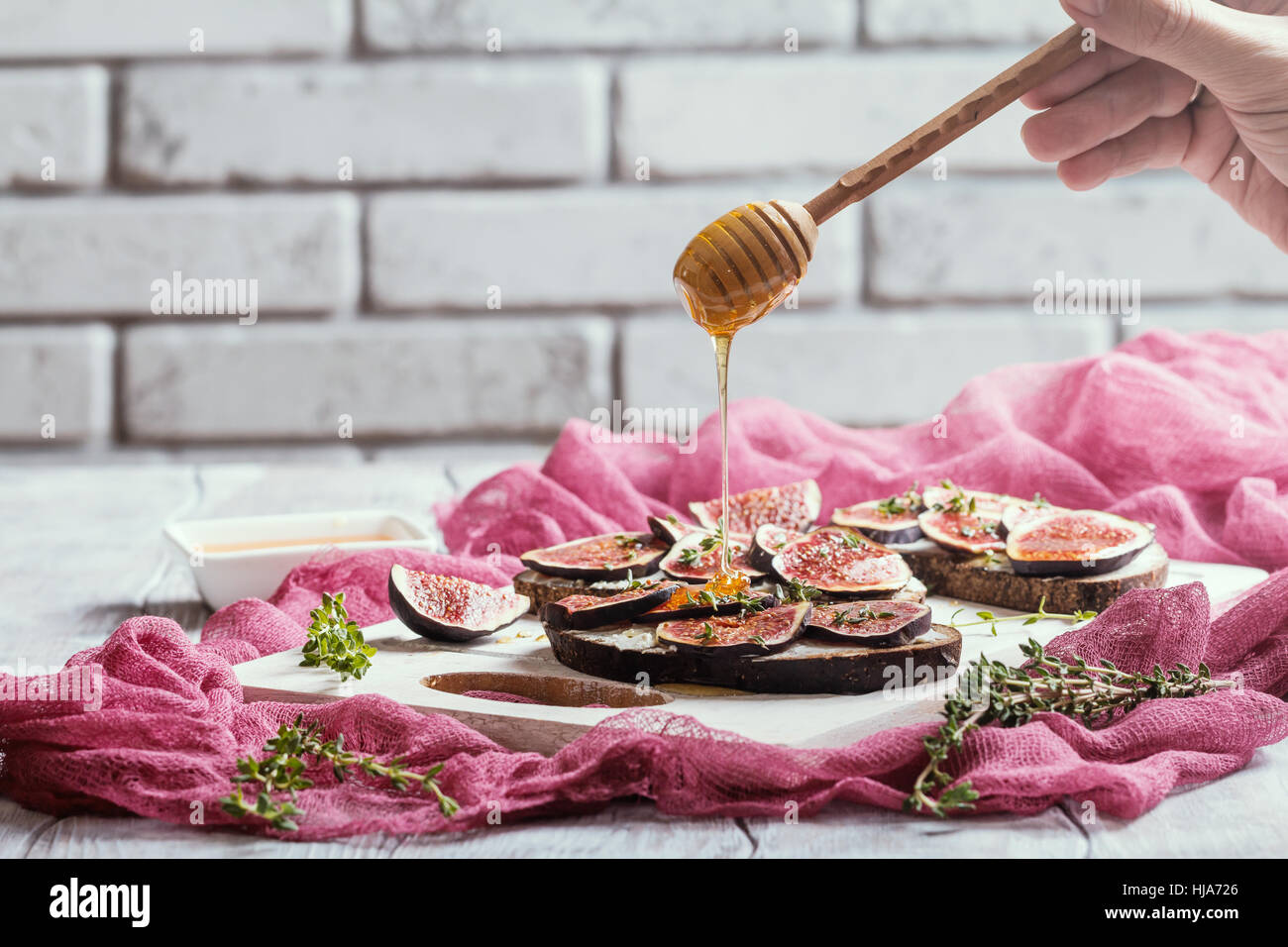 Fresh bread with figs, ricotta and honey on white cutting board Stock Photo