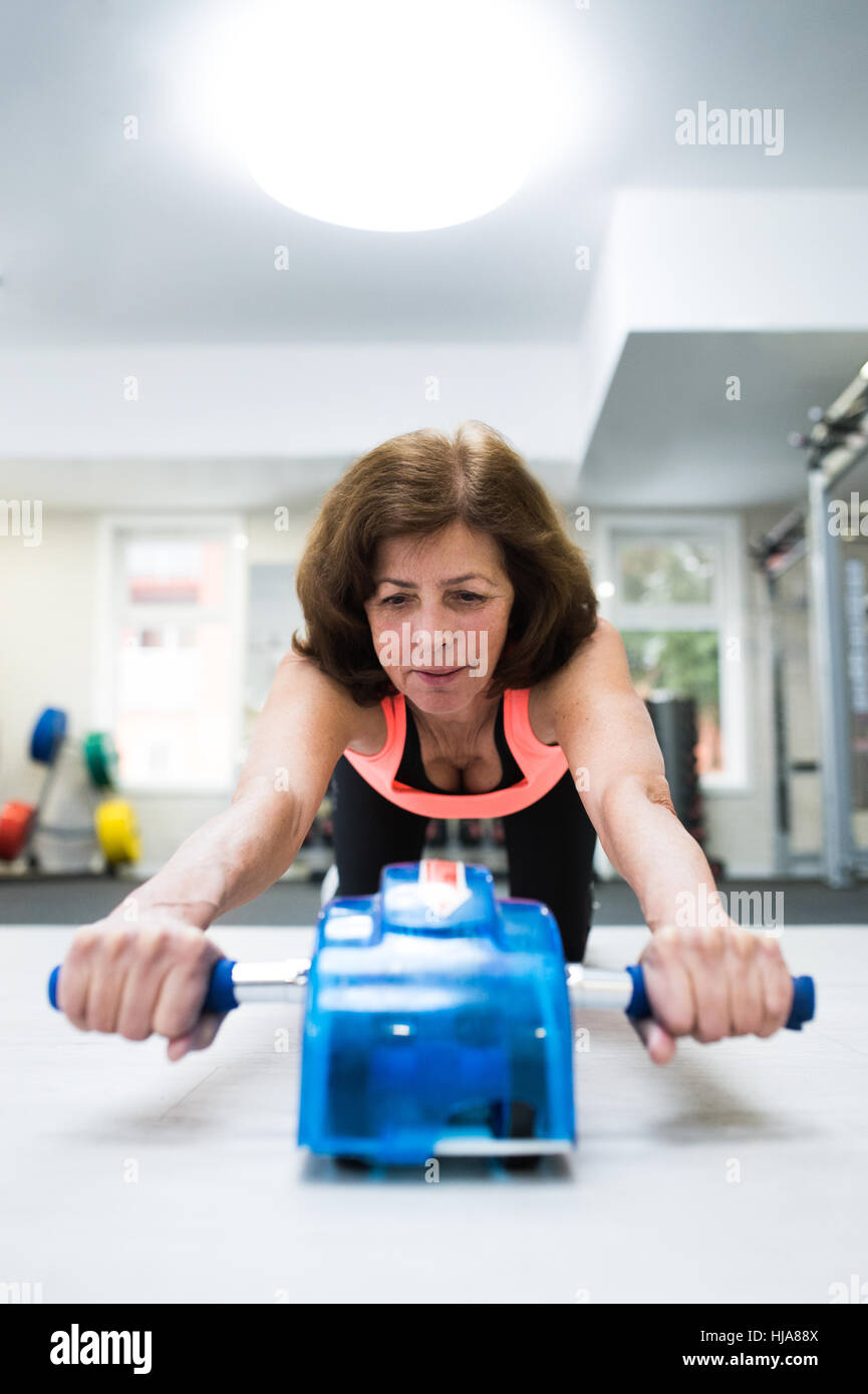 Senior woman in gym exercising abs with wheel roller Stock Photo - Alamy