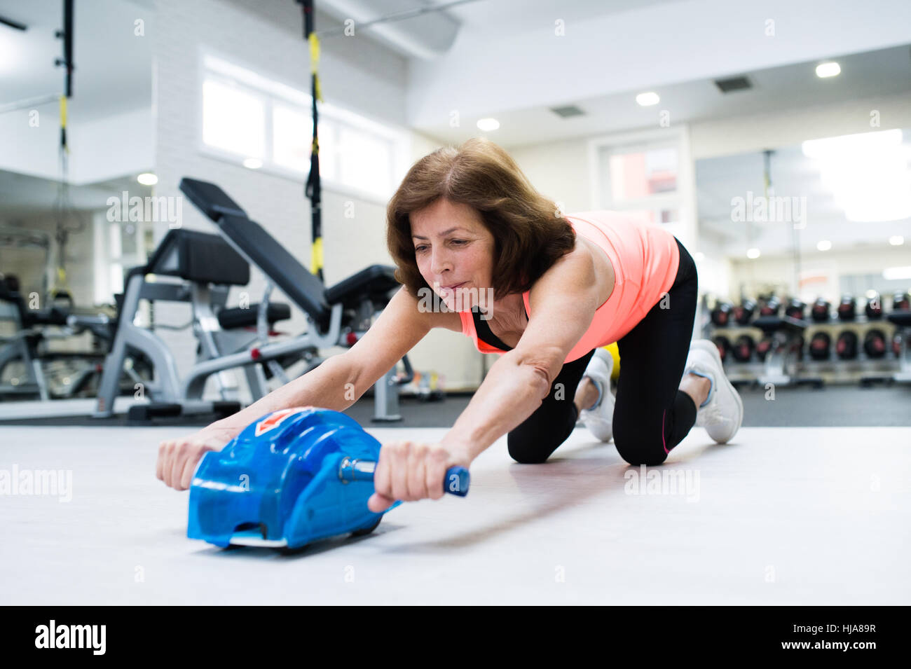 Senior woman in gym exercising abs with wheel roller Stock Photo - Alamy