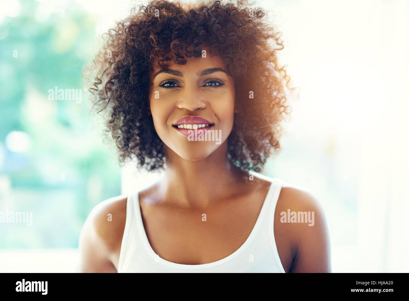 Upper body portrait of smiling young black woman in sunshine with copy ...