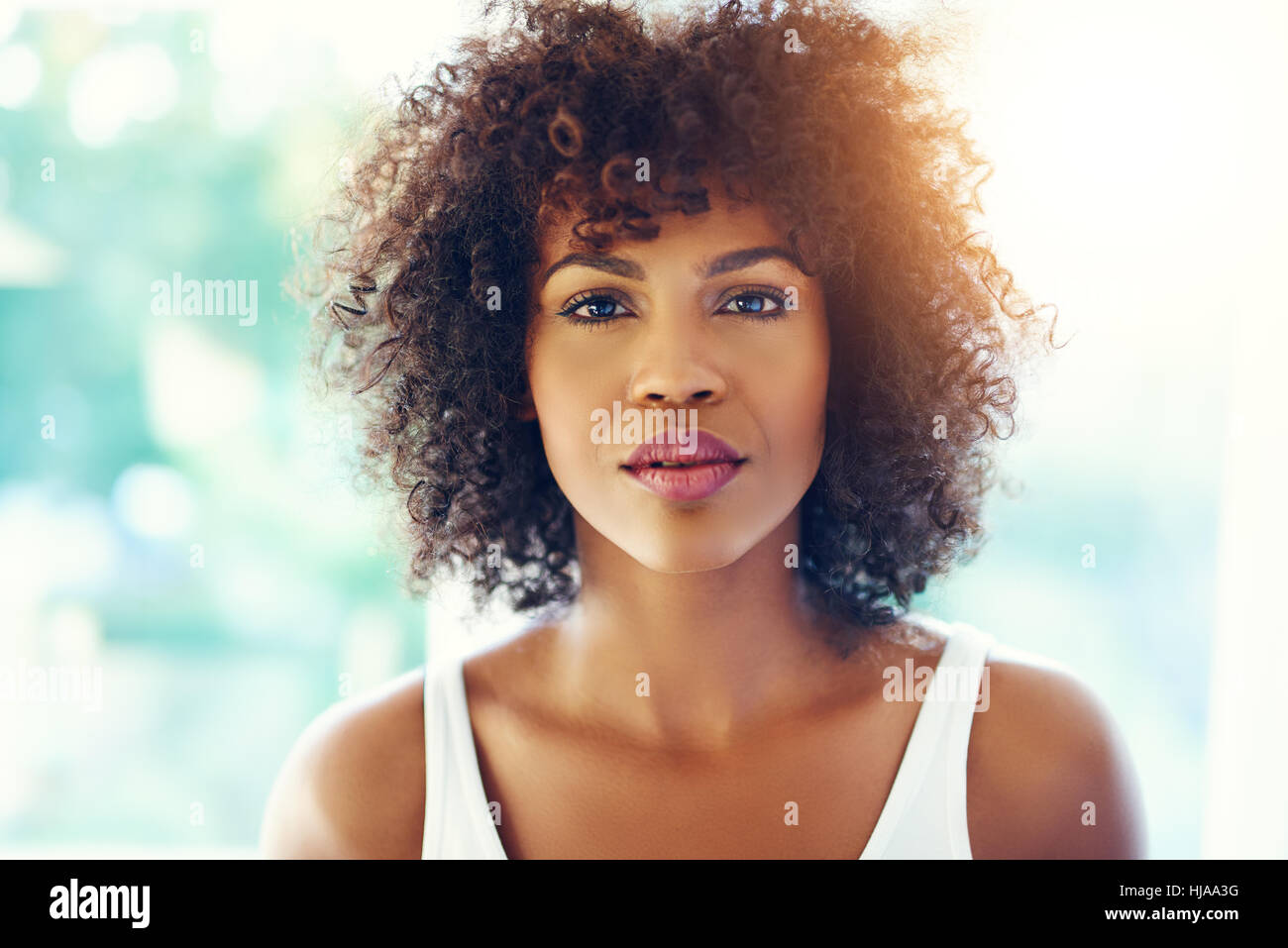 Head and shoulders portrait of thoughtful young black woman in bright ...