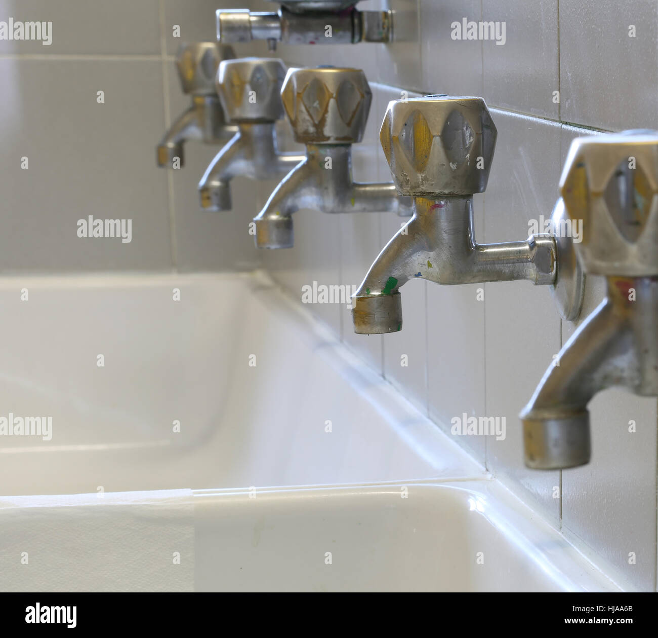 series of many dirty of colored paint stainless steel taps in a sink of