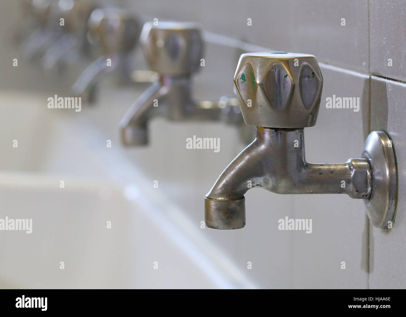 series of many dirty of colored paint stainless steel taps in a sink of