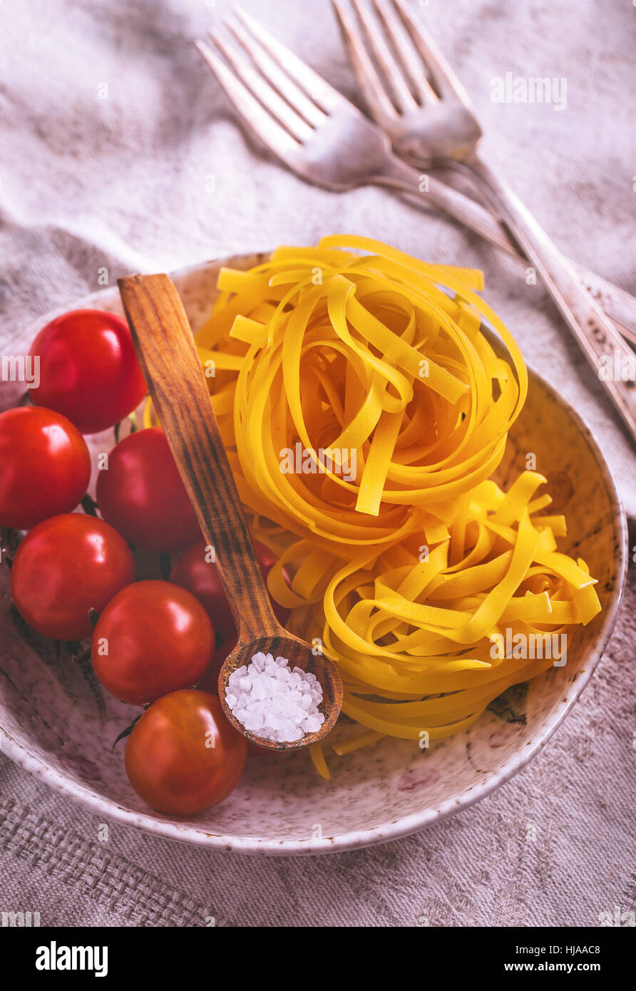 Uncooked tagliatelle pasta with cherry tomatoes Stock Photo