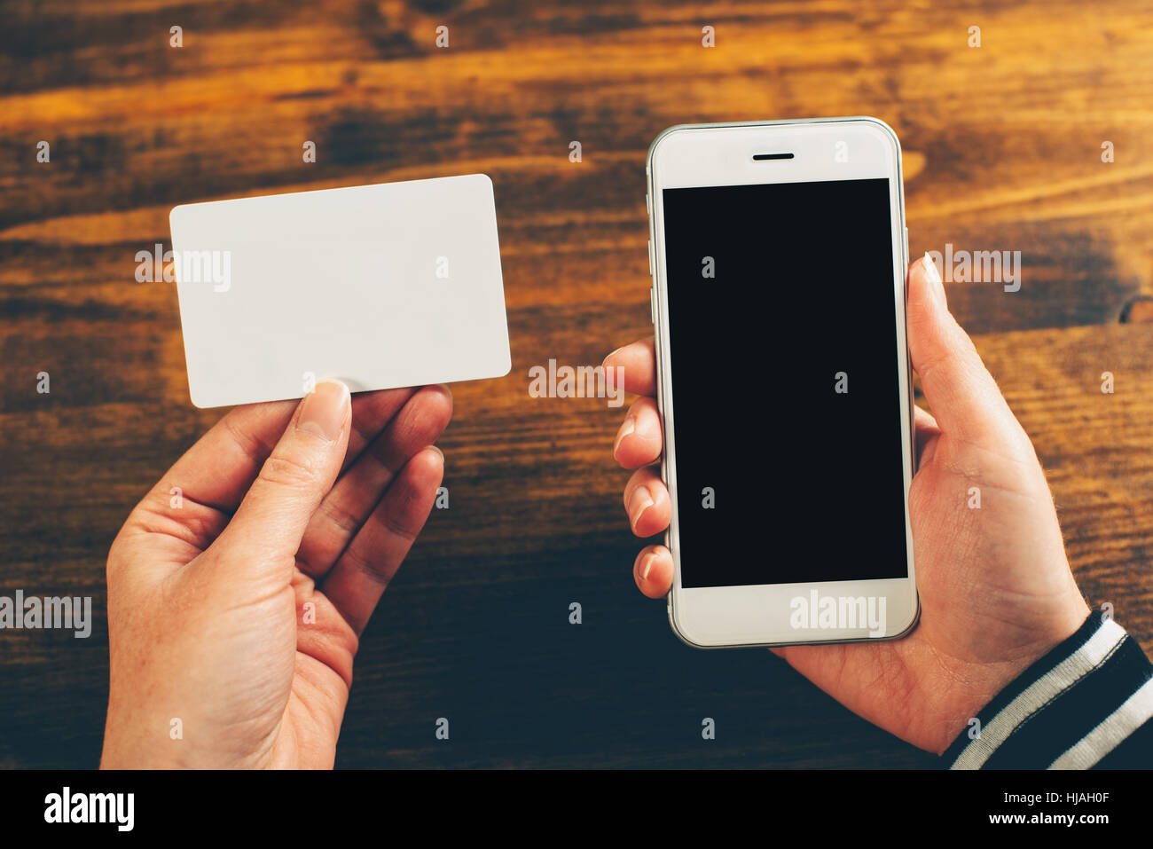 Woman holding blank business card and mobile phone with empty screen as mock up copy space for contact information and number to dial Stock Photo