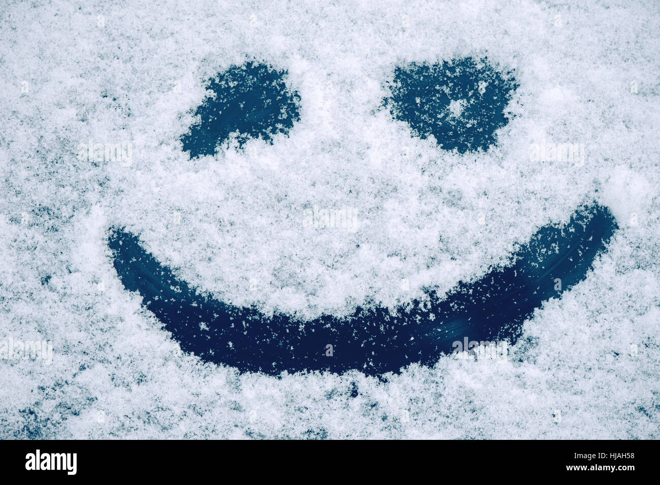 Happy smiley emoticon face in snow, winter season joy and happiness concept Stock Photo