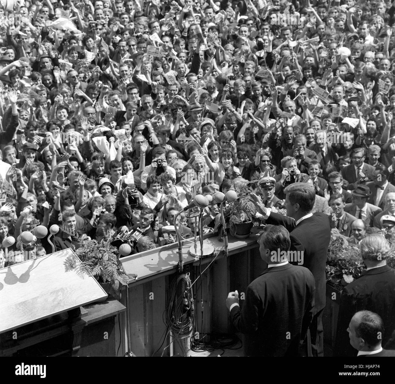 The US president John F. Kennedy (right, at the lectern, waving) and the governing Mayor Willy Brandt (to his left) are standing on front of the city hall Schöneberg of West Berlin, where tens of thousands of people cheer Kennedy. Stock Photo