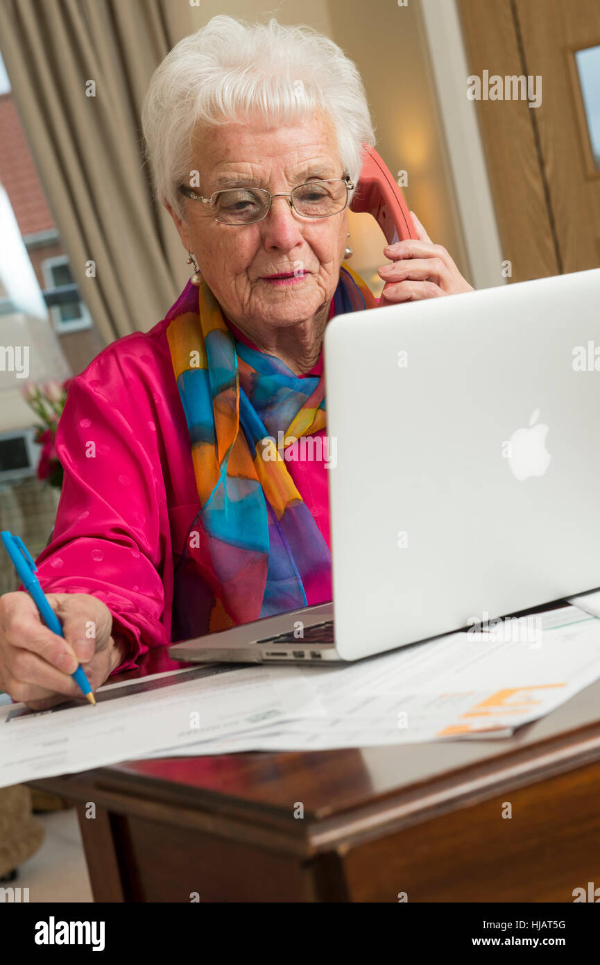 An older lady organising her monthly outgoings in her home in an effort to save money Stock Photo