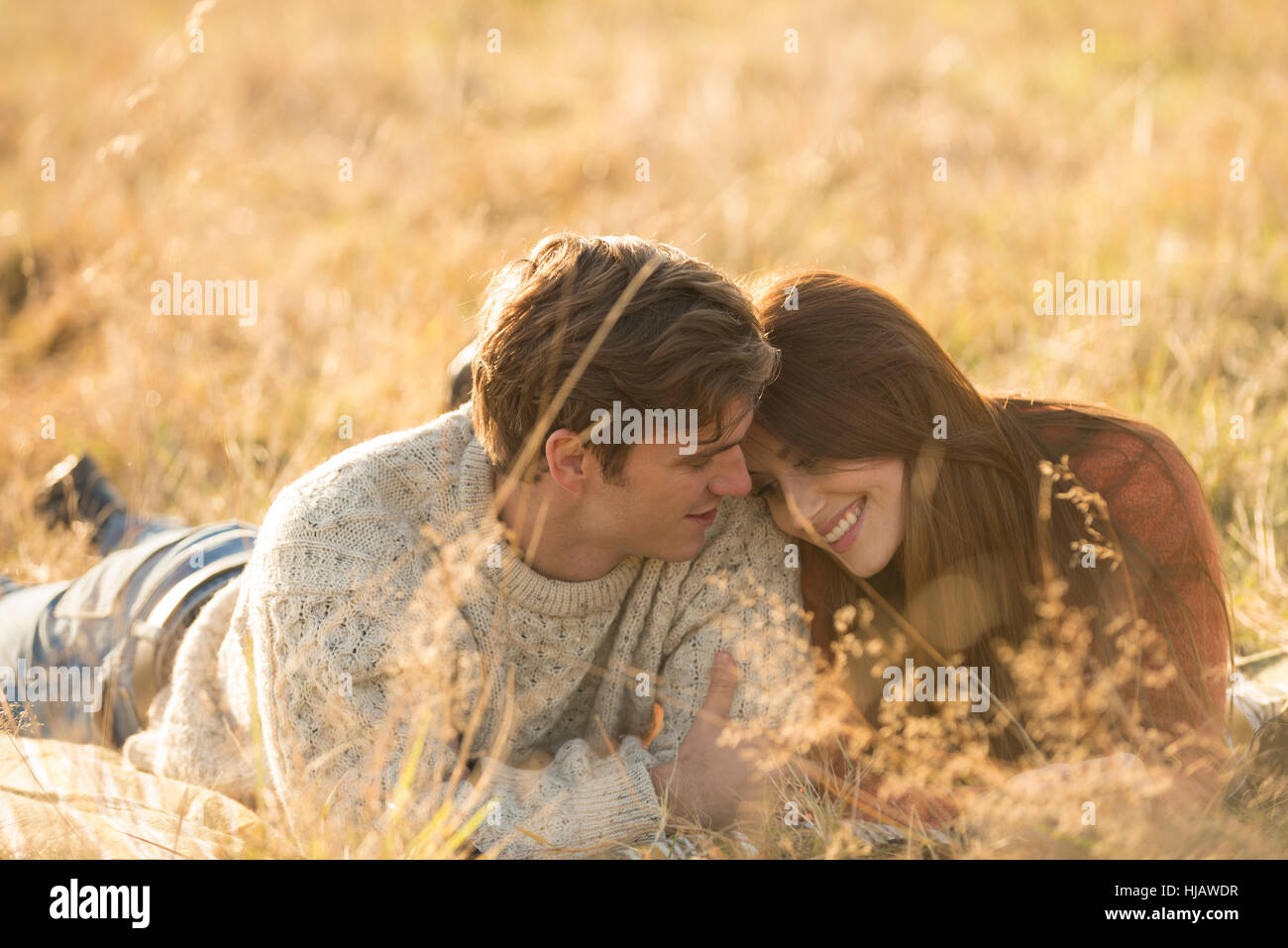 Young couple lying in field, smiling Stock Photo