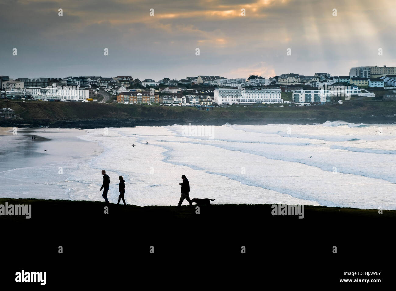 People seen in silhouette as they walk along the coastal path overlooking Fistral Beach in Cornwall, England, UK. Stock Photo