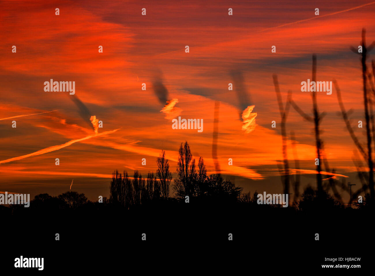 Spiral shaped clouds causing shadows on other clouds in red dawn Stock Photo