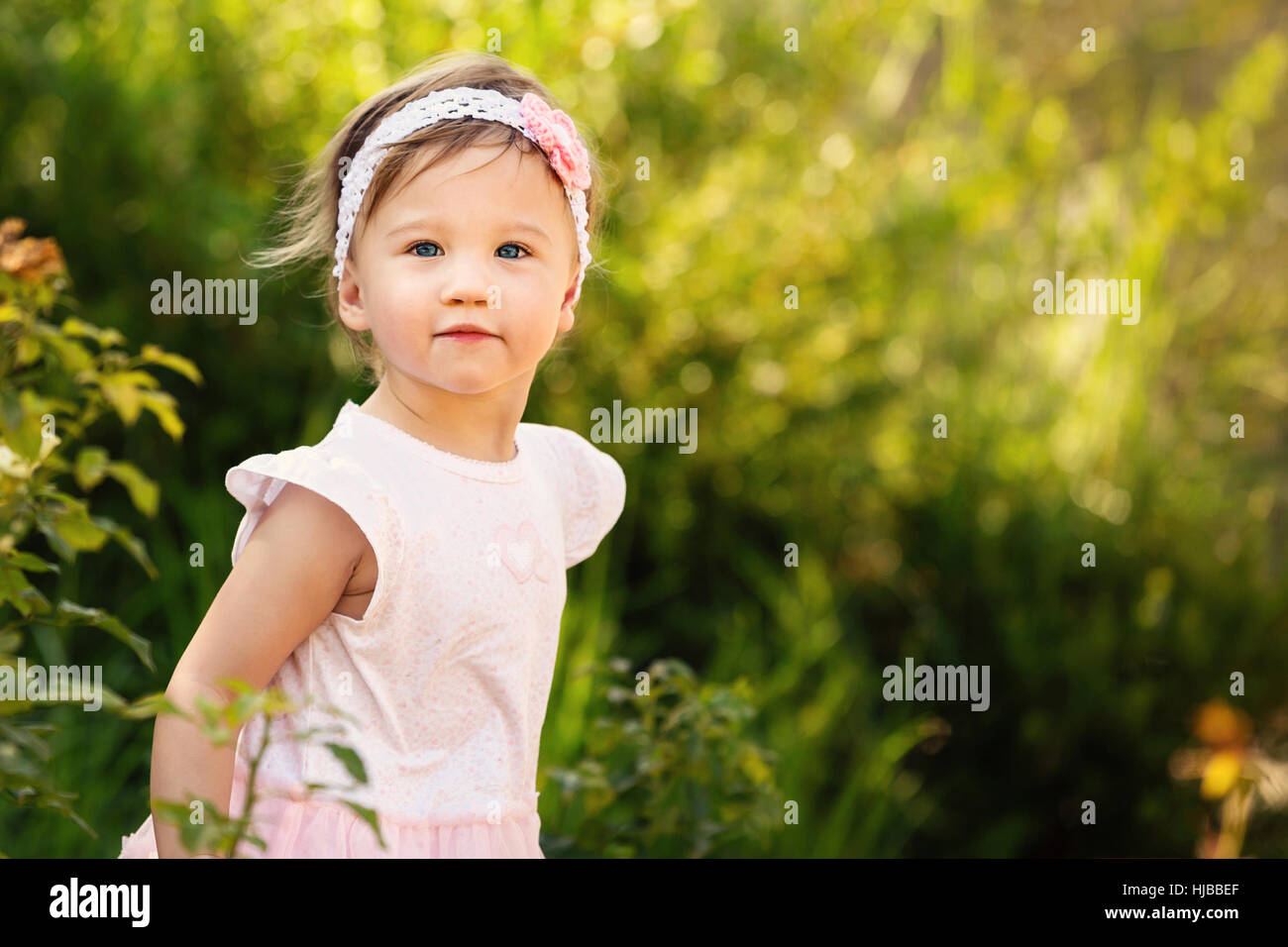 Gorgeous little girl outdoors in green garden Stock Photo - Alamy