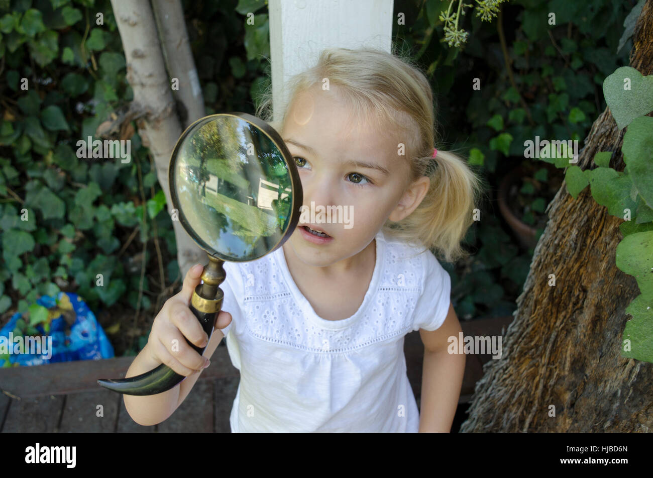 Young girl looking through magnifying glass Stock Photo - Alamy