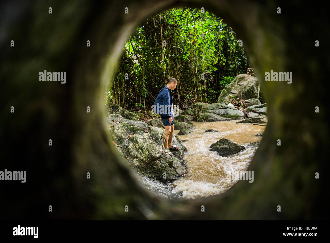 Young man watching flowing stream, Secret Buddha Garden, Koh Samui, Thailand Stock Photo