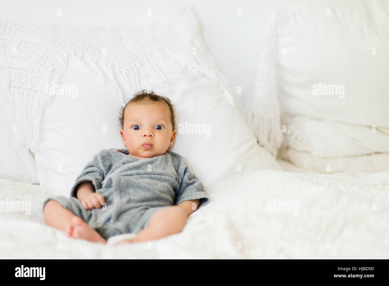 Baby sitting up on bed Stock Photo