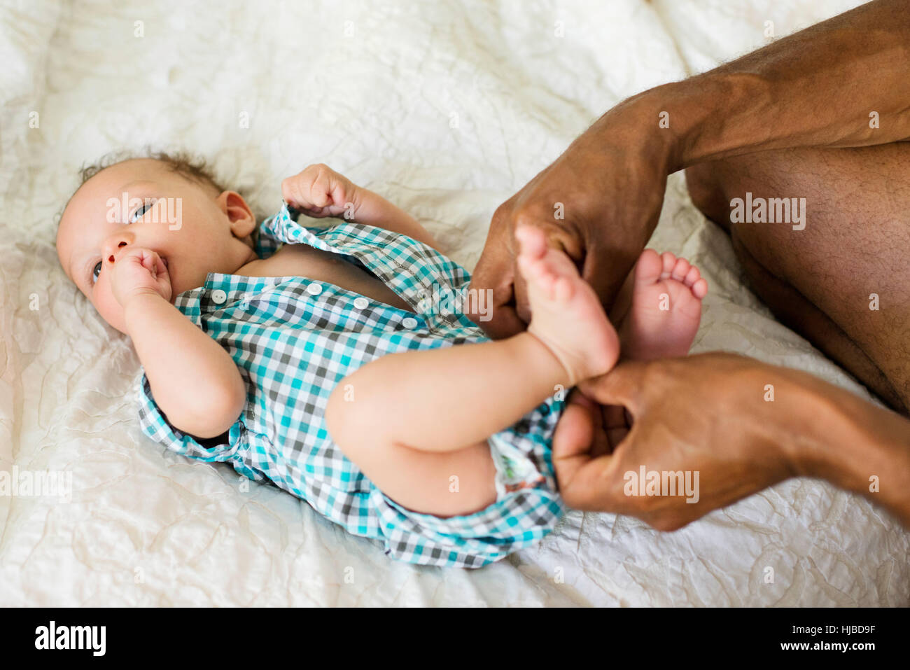 Father dressing up baby in bed Stock Photo