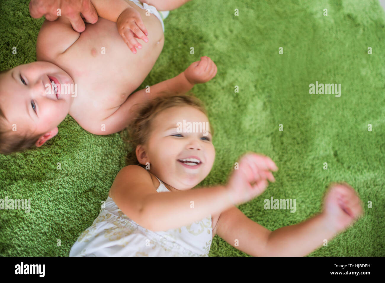 Siblings playing on green carpet Stock Photo