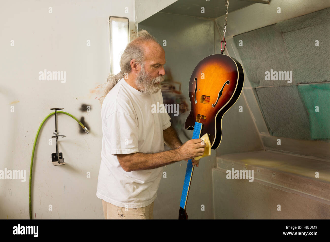 Guitar maker in workshop using cloth to varnish guitar Stock Photo