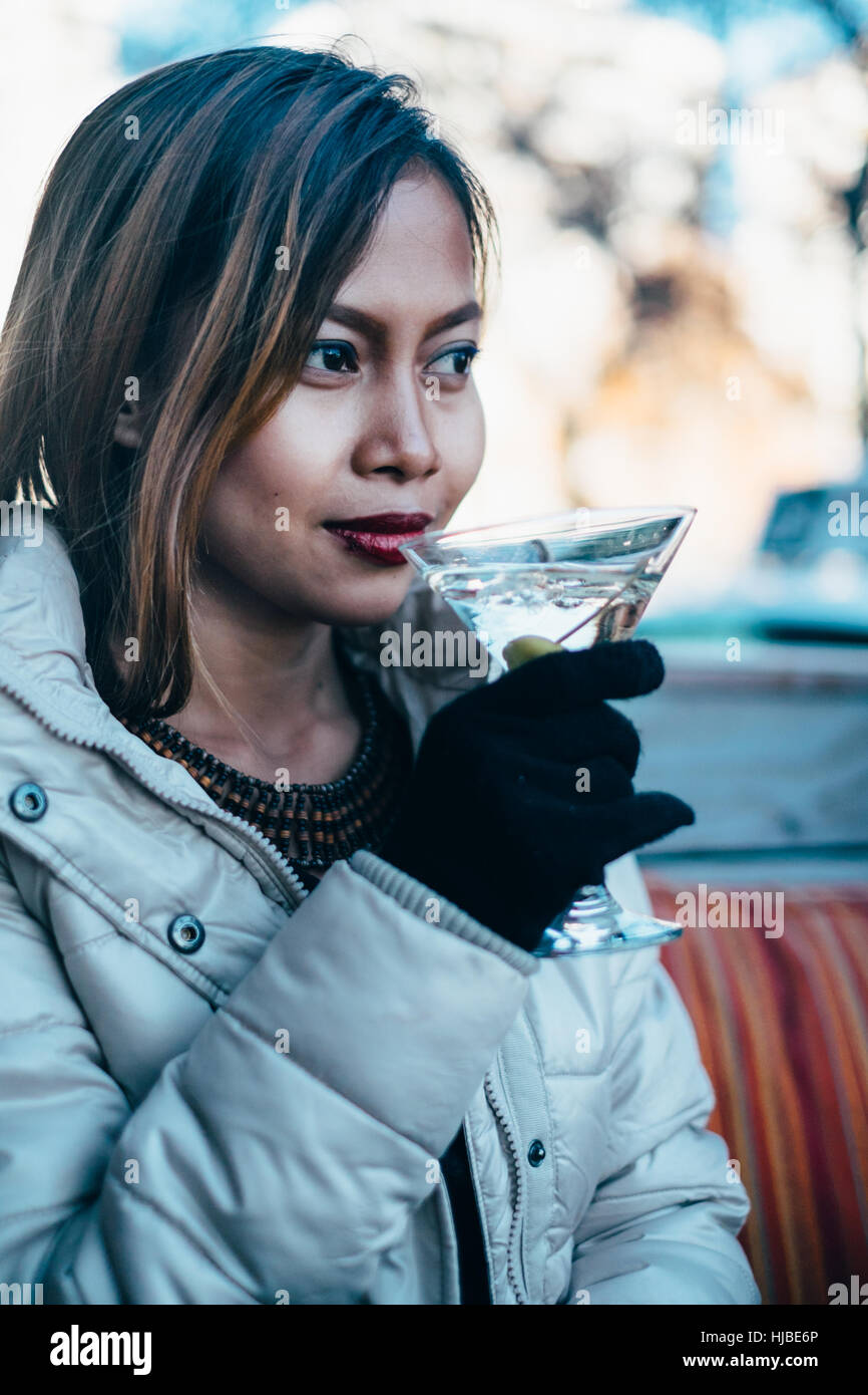 Beautiful adult girl drinking Martini outdoor , early spring Stock Photo