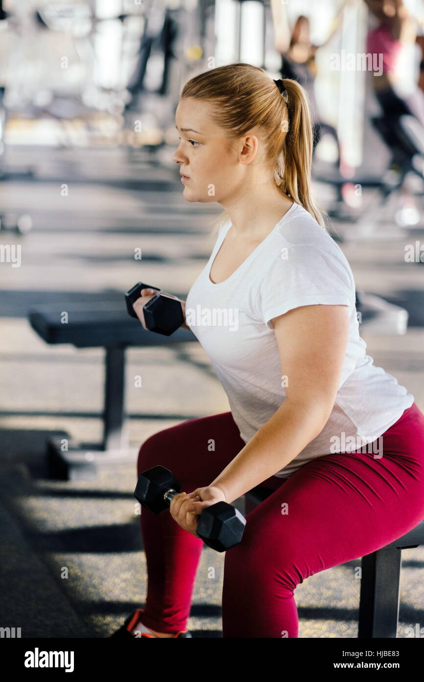 Beginner chubby girl exercising in fitness club Stock Photo