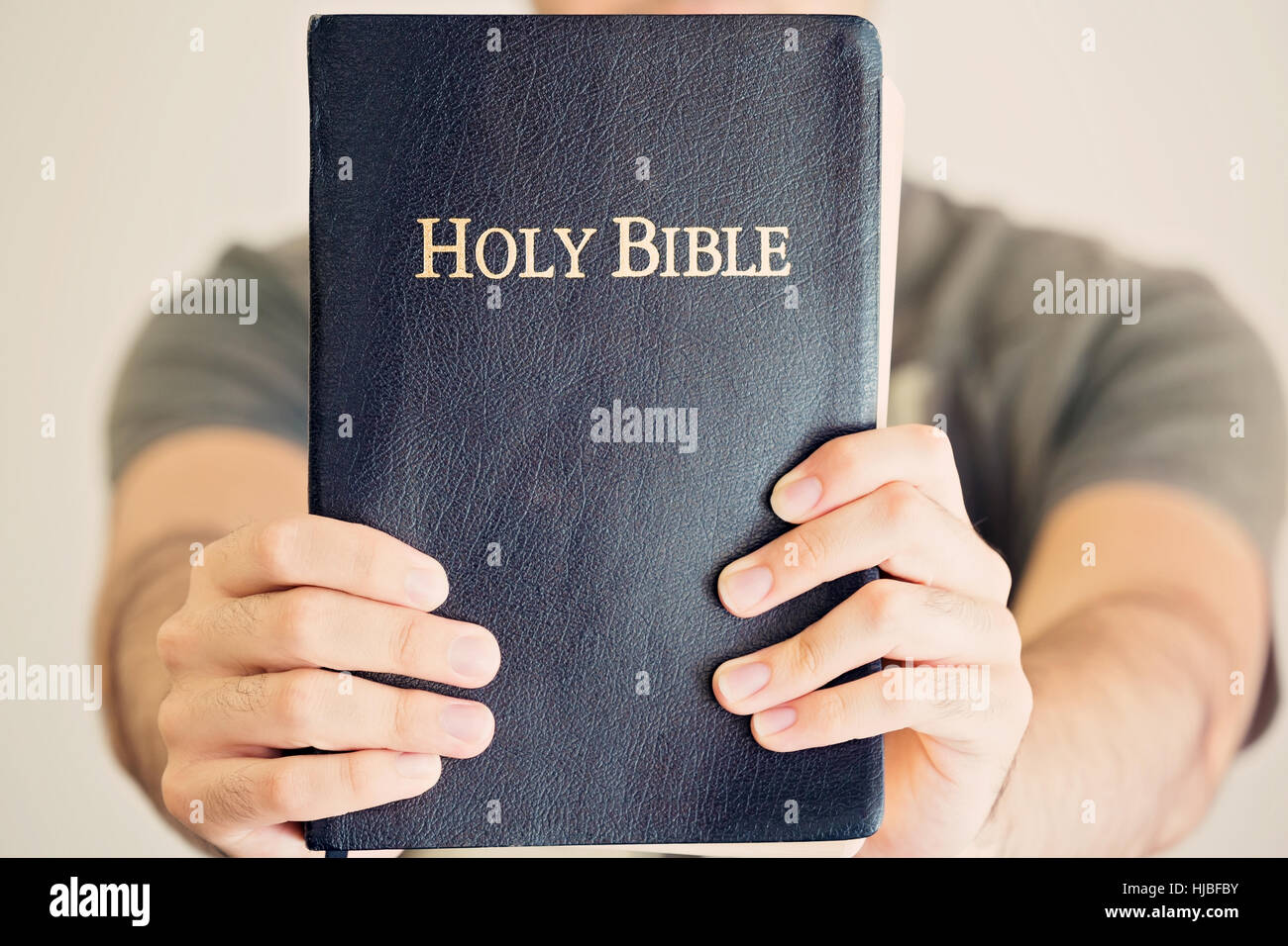 Close up of a young man proudly holding out his Bible Stock Photo