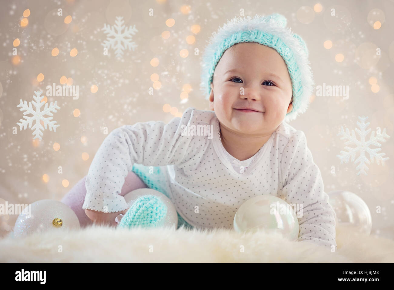 Cute Baby girl posing and smiling with Christmas snowflake ornaments and balls Stock Photo