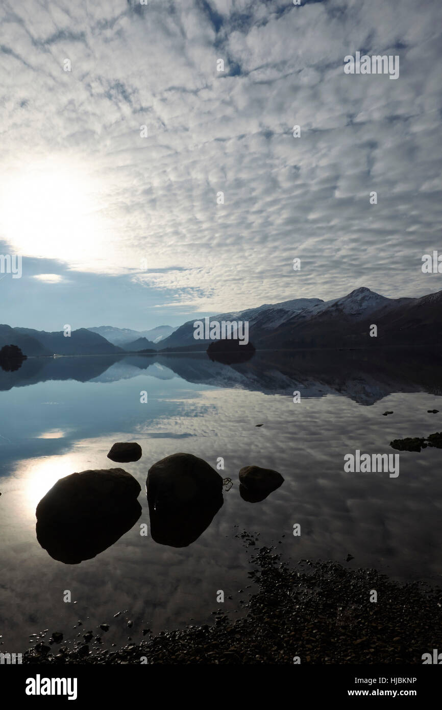 Mountains rocks and trees reflected in the calm surface of Derwent Water, Keswick, Cumbria, Lake District, England UK Stock Photo